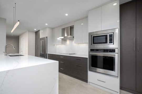 Spacious luxury kitchen with white cabinetry and a central marble island in a Toronto home