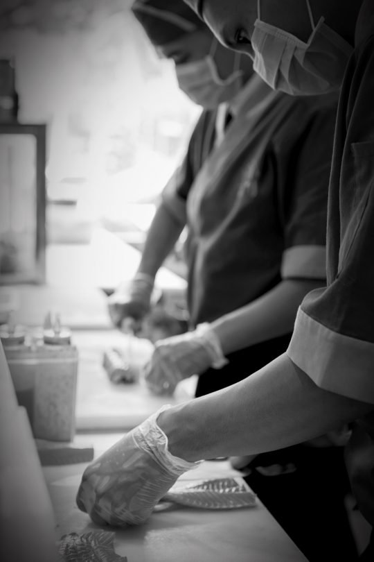 Portrait of chef flambéing a dish in a professional kitchen, styled for a fine dining branding shoot