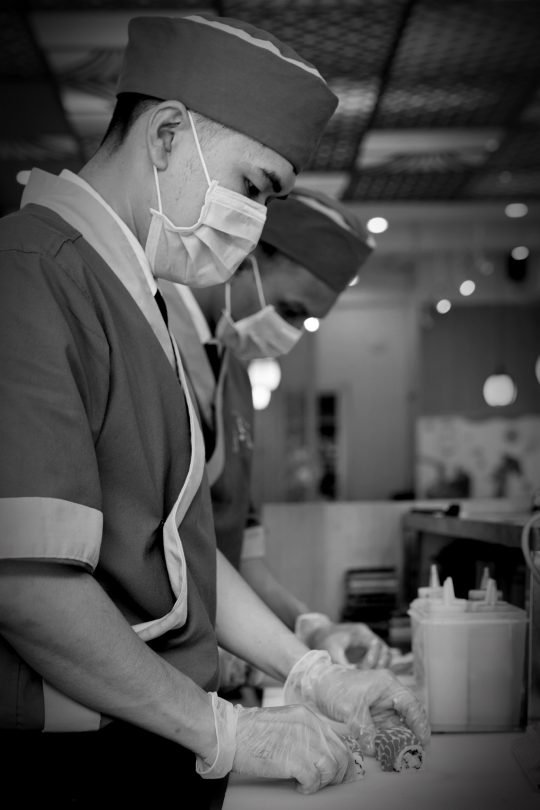 Portrait of chef flambéing a dish in a professional kitchen, styled for a fine dining branding shoot