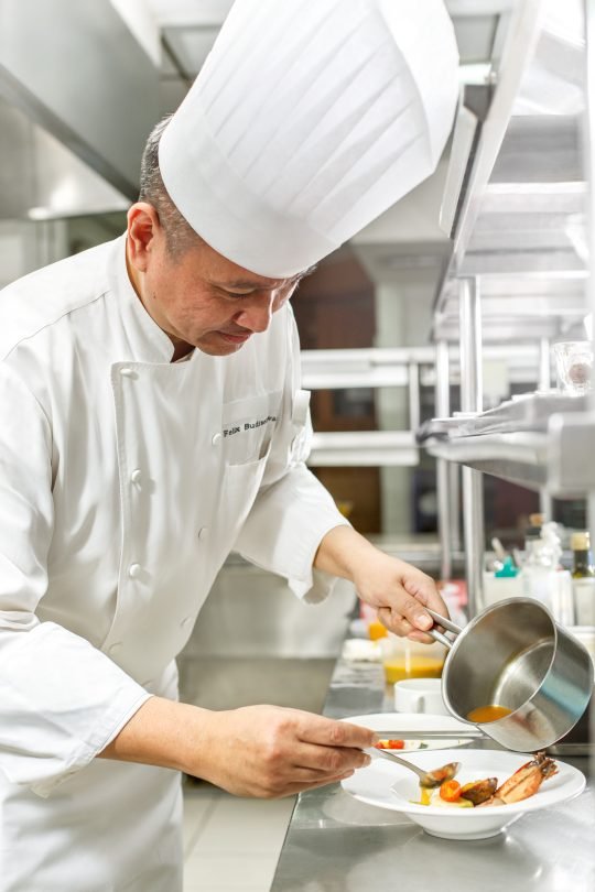 Professional chef in action plating a gourmet dish, photographed in a Toronto restaurant kitchen