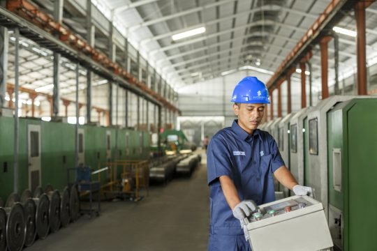 Portrait of factory worker wearing safety gear, operating machinery in an industrial workshop