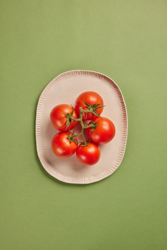 Fresh heirloom tomatoes on a wooden cutting board, photographed for a farm-to-table brand in Toronto