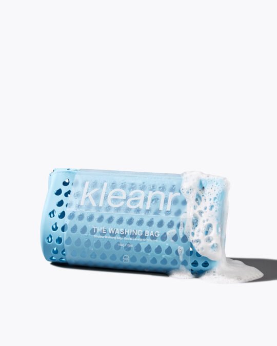 Commercial product photography of a blue washing bag with foam and bubbles on white background.