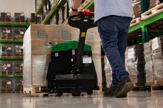 Industrial or manufacture photography capture one dramatic low-angle looking up at the worker walking with the pallet full of boxes