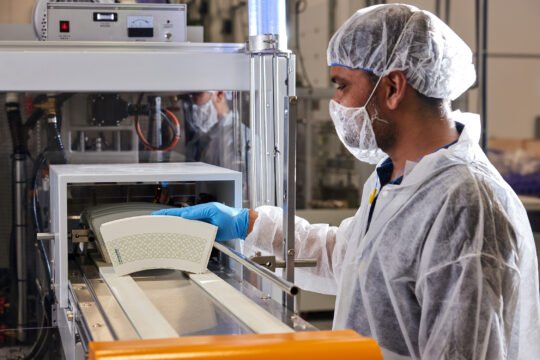 Industrial photography Focus on clean white food-safe paper rolls, hygienic stainless steel machinery, workers wearing full sanitary uniforms, gloves, hairnets, and masks. The environment should look clean, organized.