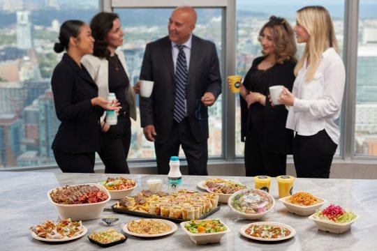 Coworkers enjoying lunch together in a modern Toronto office, photographed for a corporate catering brand