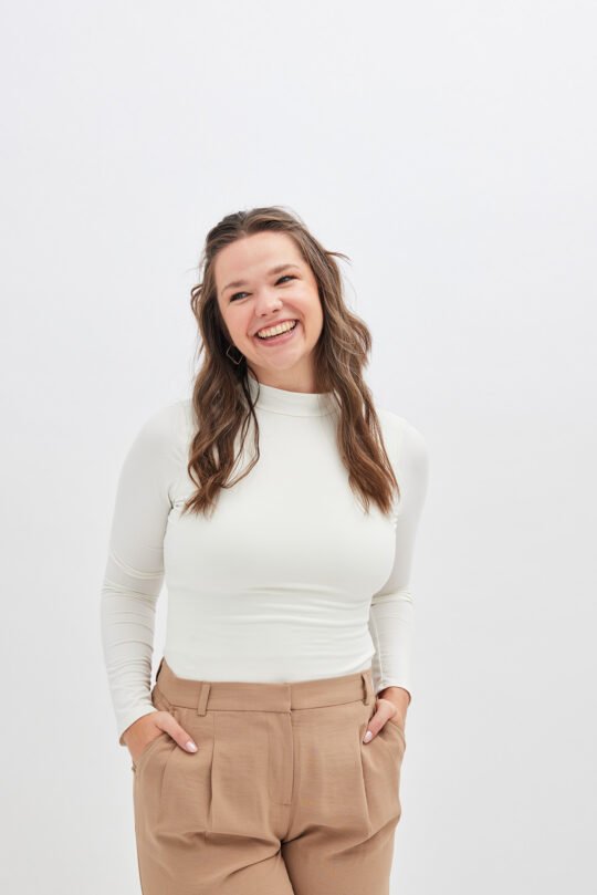 Portrait headshot of a young woman standing with white and light brown casual outfit, pose with smile on the white background