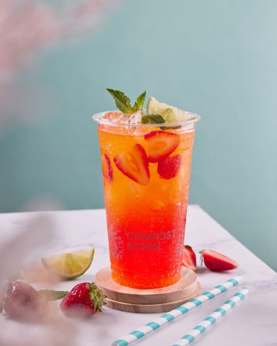 Strawberry lemonade served in a mason jar with ice and fresh fruit, perfect for a refreshing summer ad